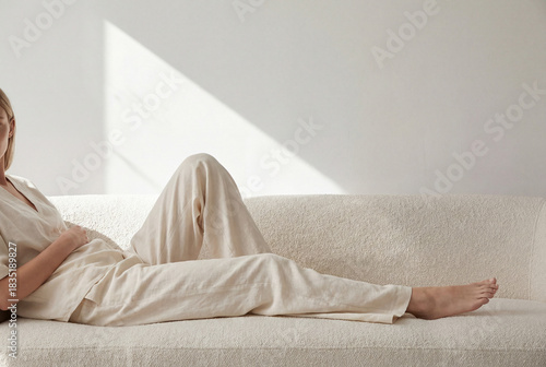 Relaxed person lounging on a textured sofa in soft natural light, minimalist home interior with neutral loungewear and calm afternoon mood for wellness and slow living concepts