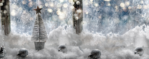 Christmas decoration in the snow in front of a glass of window with little si...