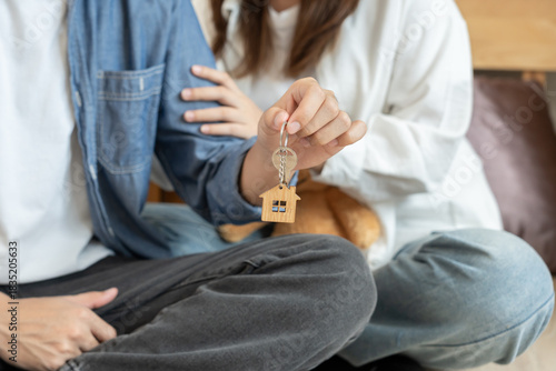 Moving house, relocation. Couple hold key house keychain in new apartment, inside the room was a cardboard box containing personal belongings and furniture. move in the new apartment or condominium