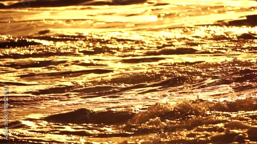 Water waves golden sunlight reflecting and shimmering on the surface of the sea creating a tranquil and beautiful natural background