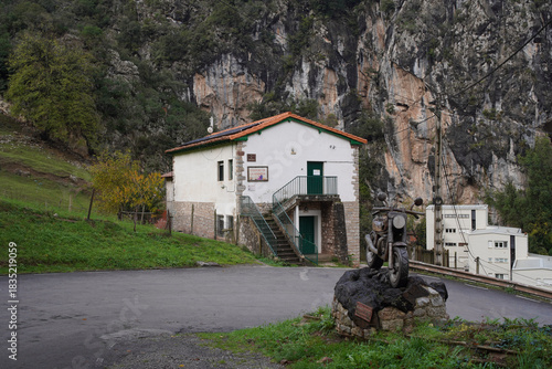 Limestone Cliffs Overlook Rural Village in Pine Forests - Here is a revised description that adheres to the critical rules: Small village with grey building, surrounded by natural limestone walls,.