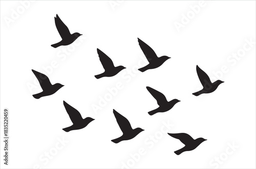 A flock of black birds flying in a scattered formation on white