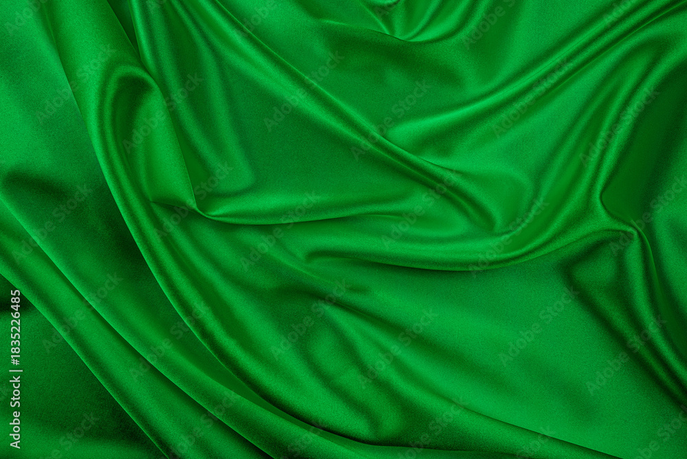 Obraz premium A lush vibrant green satin or silk fabric is draped and folded, creating elegant waves, texture, and highlights perfect for a luxurious abstract background.
