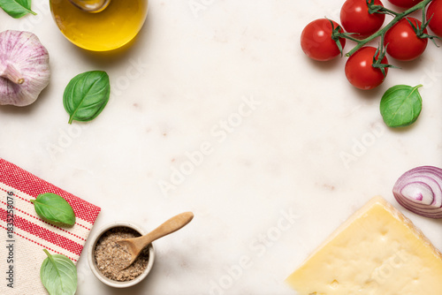 Italian cooking ingredients on marble background:  tomatoes, parmesan cheese, olive oil, garlic, red onion and basil top view
