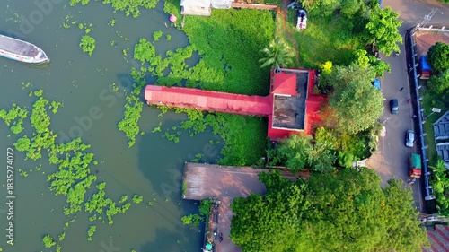 Wallpaper Mural Aerial view of a vibrant red boat jetty station surrounded by lush green foliage on a lake backwater in Kerala, India. A boat docks at the pier. Torontodigital.ca