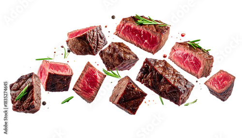 Delicious grilled beef steak pieces falling with aromatic herbs and peppercorns on white background