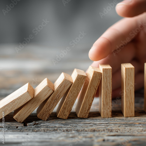 A hand halts the cascade of tumbling dominos, symbolizing effective change management, risk reduction strategies, decisive leadership actions, and smooth organizational transformation.