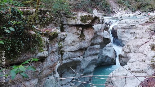 Clear water cascades from top of rocky outcrop surrounded by rocky shore.