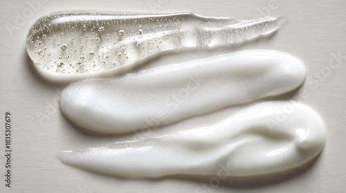 Three distinct textures of moisturizing gels and creams are artfully arranged on a smooth surface. The reflections and bubbles create an inviting look, Cloud Dancer Color of the Year