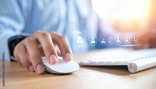 Professional hands using a computer mouse over a keyboard, interacting with digital human resource icons, symbolizing management and data.