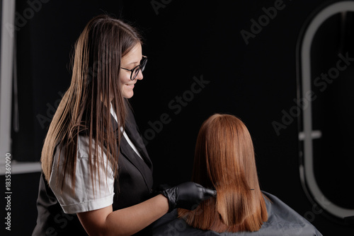 Hairdresser and client Female caucasian adult receiving keratin treatment in hair salon