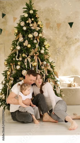 a happy family at the Christmas tree at home waiting for the new year, enjoying and hugging each other, having fun together, the new year at home