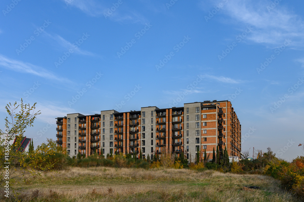 Fototapeta premium Modern Residential Complex, View from the Street or Courtyard. Building Surrounded by Urban Environment, Cars, Trees.