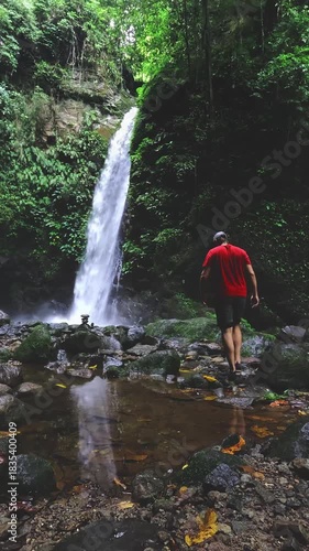 Man walking towards Casaroro waterfall with its reflection mirrored in a clear pond showing a candid authentic experience of being one with nature. Valencia, Negros Oriental, Philippines