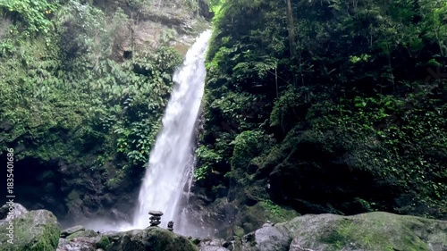 Dolly up from underwater to reveal the majestic Casaroro waterfall then moving up to the view of the lush trees framing the sky. Valencia, Negros Oriental, Philippines