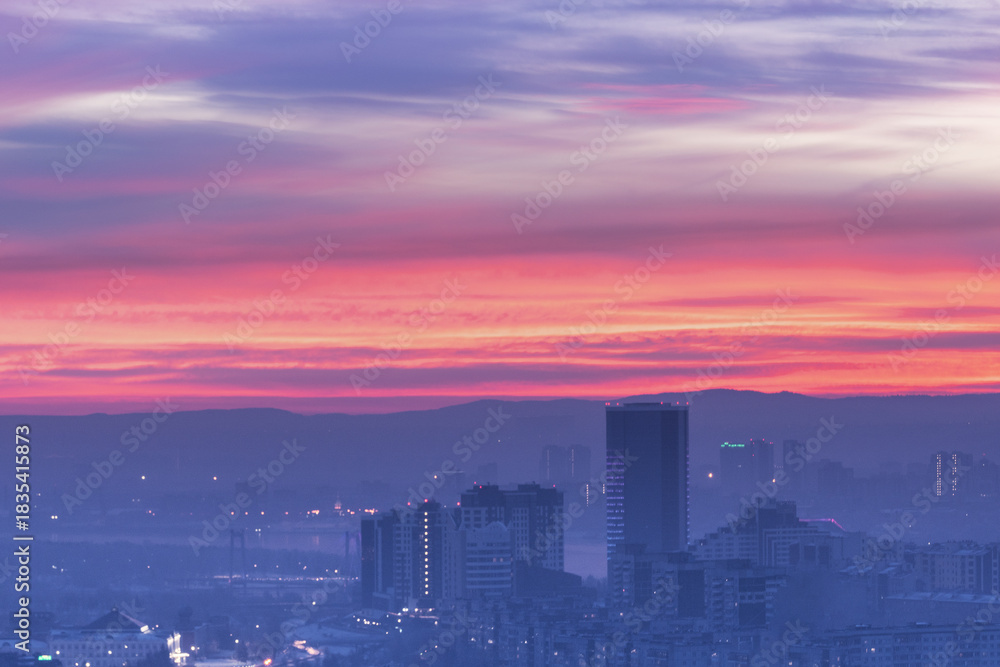 Fototapeta premium A colorful sunset illuminates the urban skyline with stunning hues, captivating beauty, Krasnoyarsk evening city at sunset panorama.