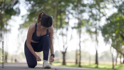 Asian adult woman prepares outdoor exercise tie running shoes natural park environment embrace fitness wellness healthy lifestyle
