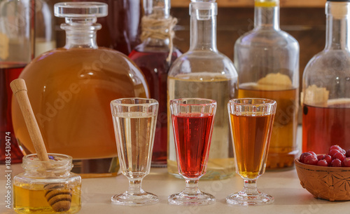 A set of homemade multicolored alcoholic tinctures and liqueurs in bottles and glasses. The bitters. Selective focus