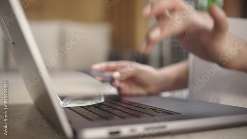 An unrecognizable woman enters credit card details on a laptop, symbolizing online payments and digital transactions. Concept security and convenience in finance