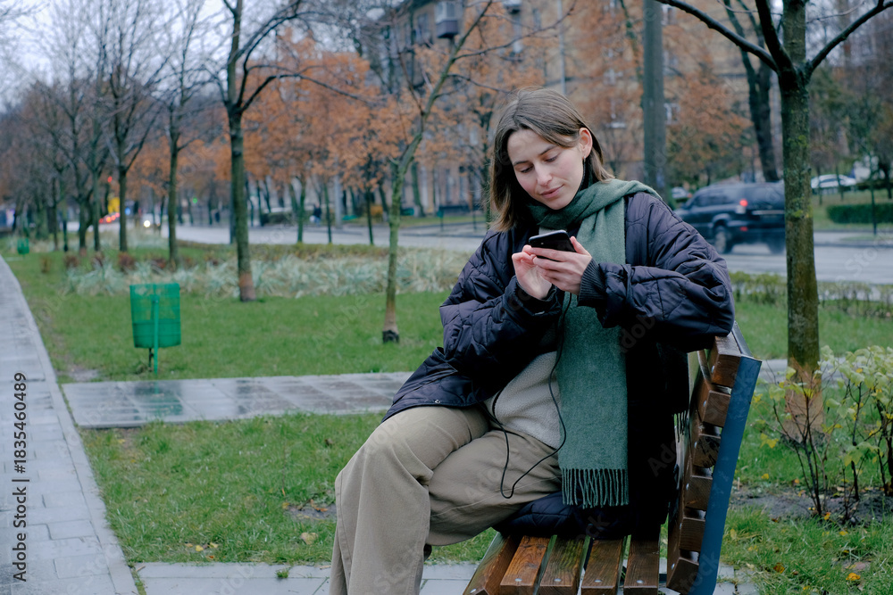Fototapeta premium Woman checking phone on bench