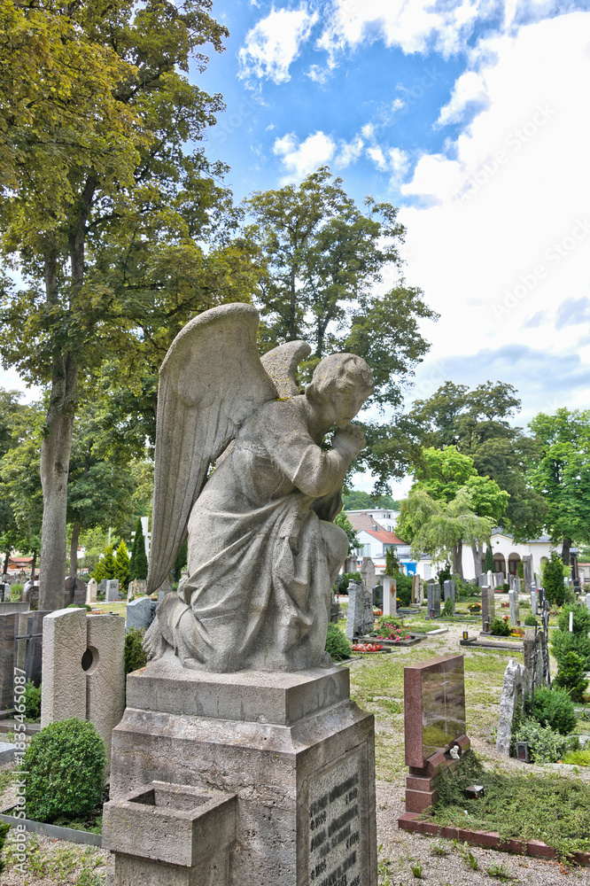 Obraz premium Großer Engel kniet betend auf einem Grabstein auf dem Friedhof in Kaufbeuren