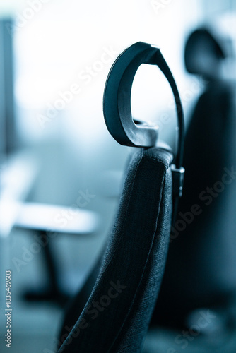 Black office chair head-rest ergonomic back support detail in soft light.