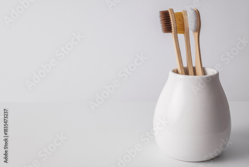 Natural eco friendly toothbrushes in ceramic holder on white background