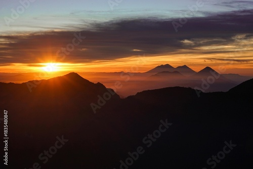 Wallpaper Mural Sunrise or sunset light illuminates the mountain landscape silhouette with orange clouds in the sky Torontodigital.ca