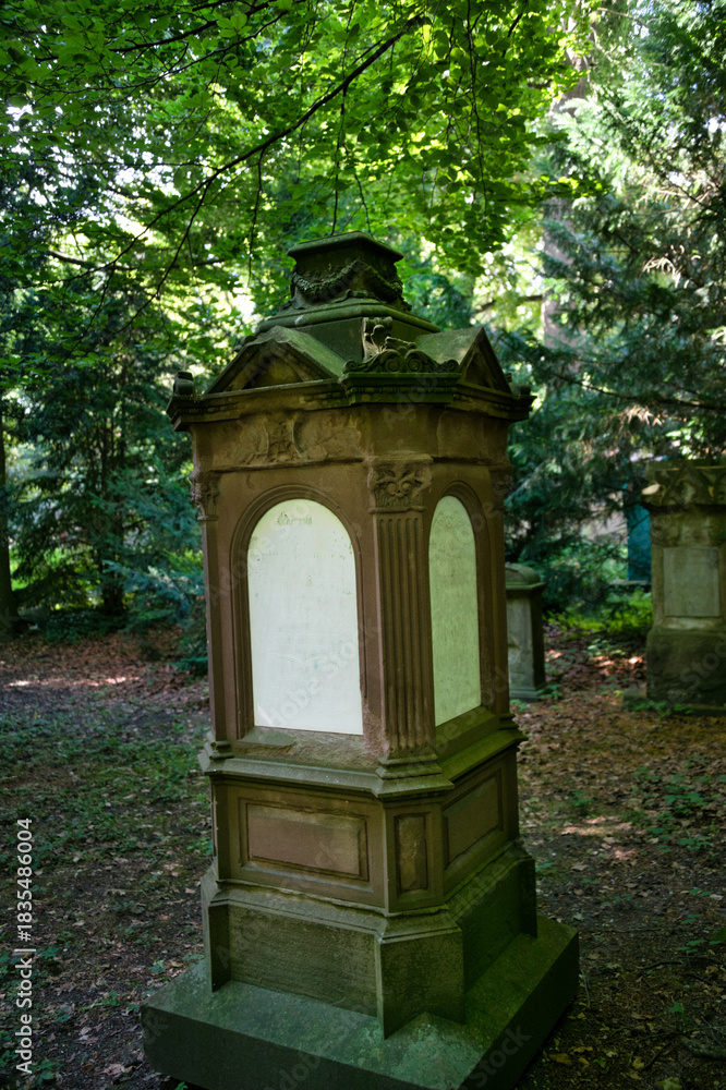 Obraz premium sehr alter dunkler Stein mit weißen Platten an allen Seiten auf einem Friedhof in Ulm