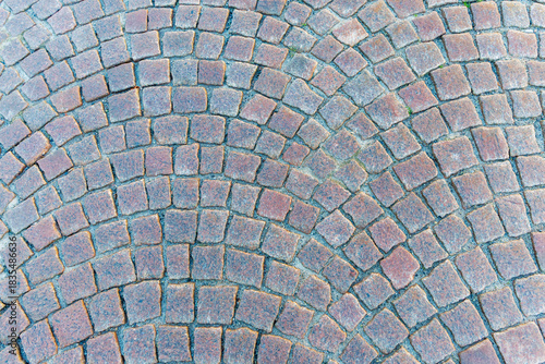 Full frame macro texture of rounded, reddish-brown cobblestone paving
