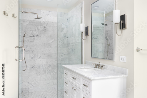 A bathroom with a white cabinet, marble countertop, and a shower with marble subway tiles.