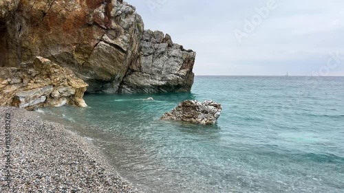 Serene coastal waves gently embrace rocky shoreline under overcast skies