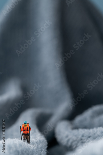 A figurine of a miniature mountain climber, set on a soft fleece surface that mimics a snow-covered landscape