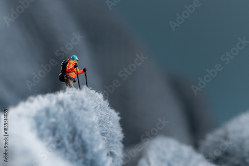 A miniature mountain climber figurine on a fuzzy fleece lining resembling a snow-covered surface, with a blurred background of a mountain or ice wall