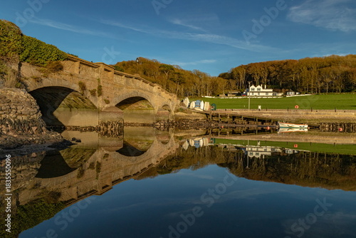 Axmouth Bridge reflected on the water of river Axe near town of Seaton, Devon