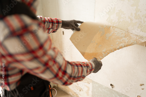 Bild auf Leinwand Close-up of worker removing old wallpaper from the wall