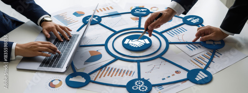 A professional team collaborates during a business meeting, analyzing data charts and utilizing laptops to strategize and discuss key insights for project success. Amity 