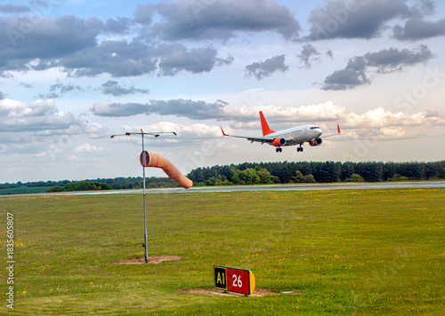 Passenger jet approaches runway near windsock at London Luton Airport