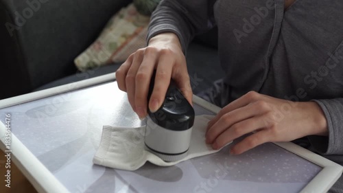 woman takes care of clothes at home, cuts off lint with tool