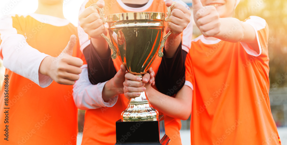Fototapeta premium Happy young female childrens football team holding trophy together