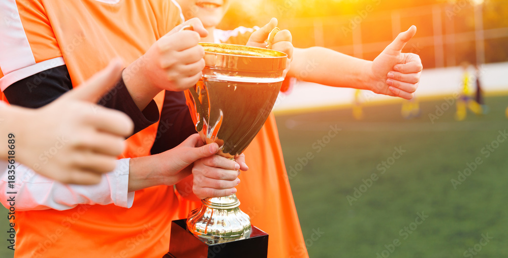 Fototapeta premium womens childrens football team celebrating victory with trophy at sunset
