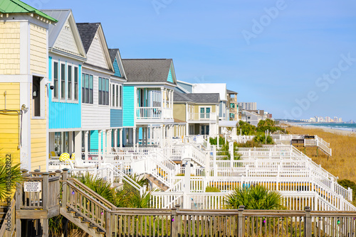 Colorful waterfront homes along the grassy dunes of the Atlantic Ocean with the Myrtle Beach skyline in the distance, in Surfside Beach, South Carolina.