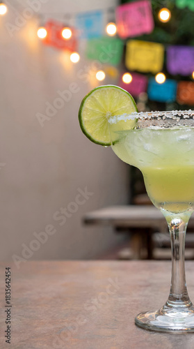 cinco de mayo festive margarita with lime and salt rim against colorful papel picado party lights
