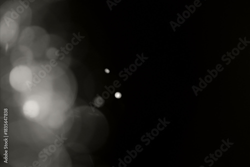 Blurry garland lights on a dark background. Festive Christmas and New Year background. Soft focus. Image toned in color of the year 2026 - Cloud Dancer.