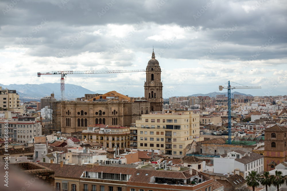 Obraz premium Urban cityscape featuring historical architecture, modern buildings, and construction cranes