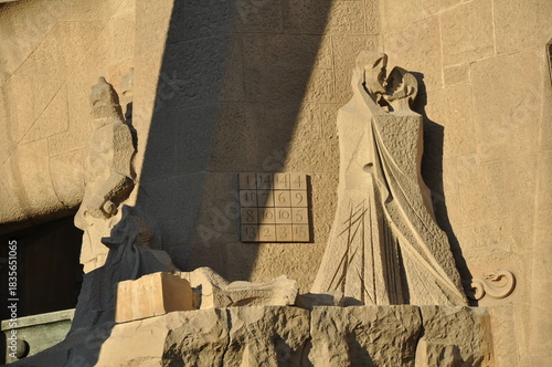 A close-up of the Passion Façade featuring the Kiss of Judas and the iconic magic square, carved by Josep Maria Subirachs at Sagrada Família in Barcelona.