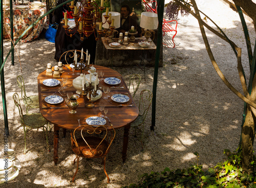 Wooden outdoor table in a garden courtyard set with vintage plates