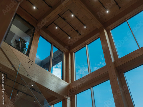 Interior architecture showing timber beam ceiling structure with large windows and track lighting overhead.