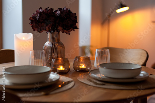 Wooden round table setting with glassware and vase creating a stylish evening atmosphere