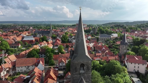 Slow drone orbit around a church spire with several nearby churches and Castle Hill on the horizon in Quedlinburg, Saxony-Anhalt, Harz region.